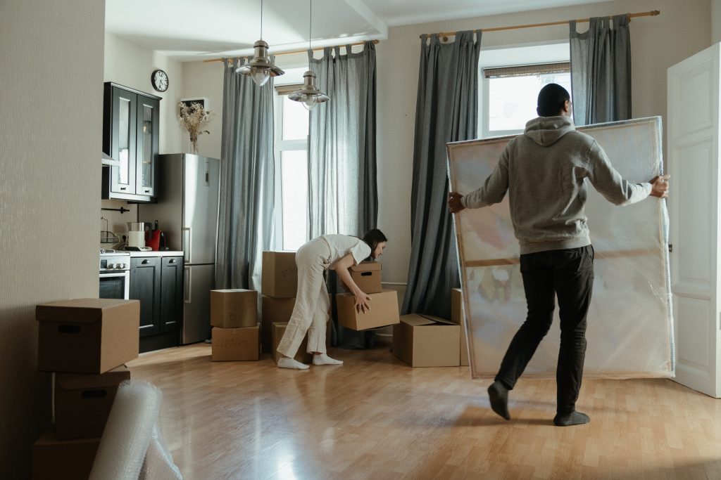 couple unpacking boxes in front of windows with drapes