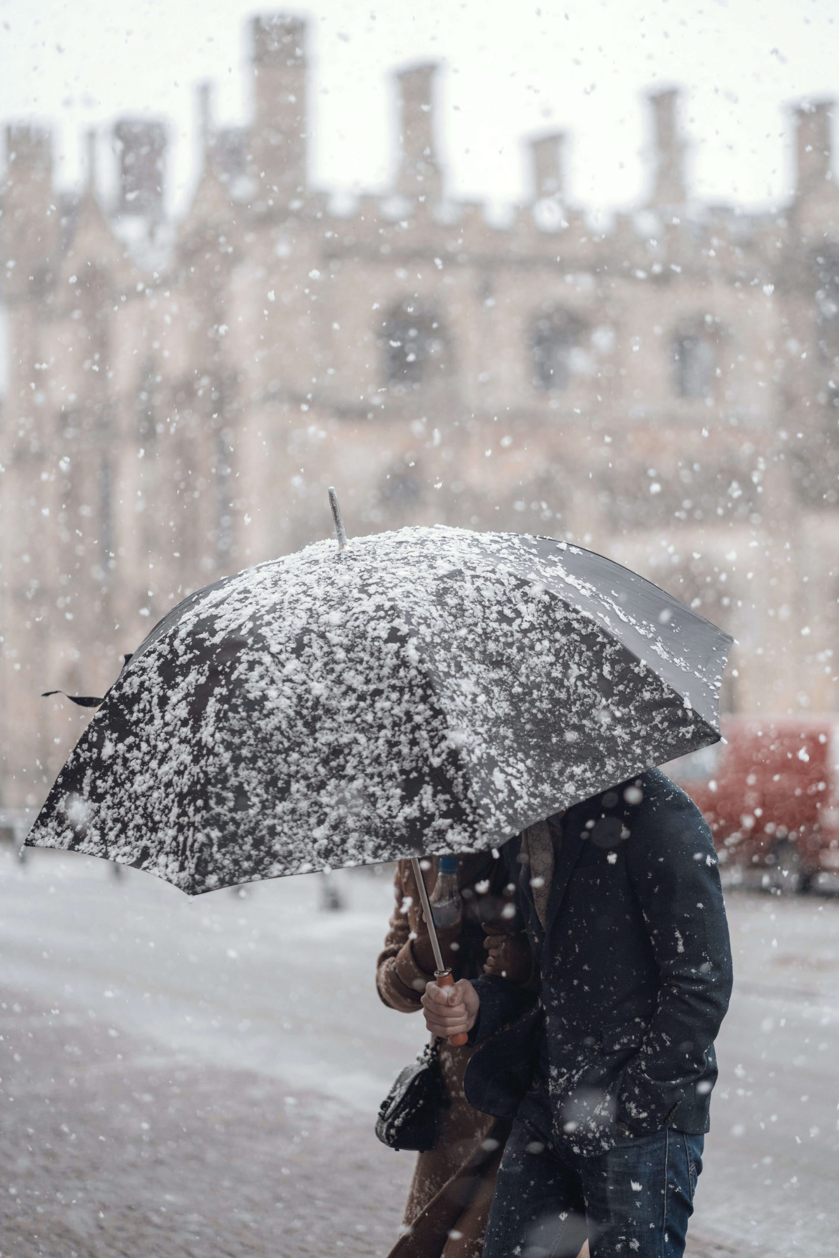 person walking through snow holding umbrella