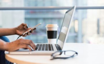 woman with cell phone and computer having coffee