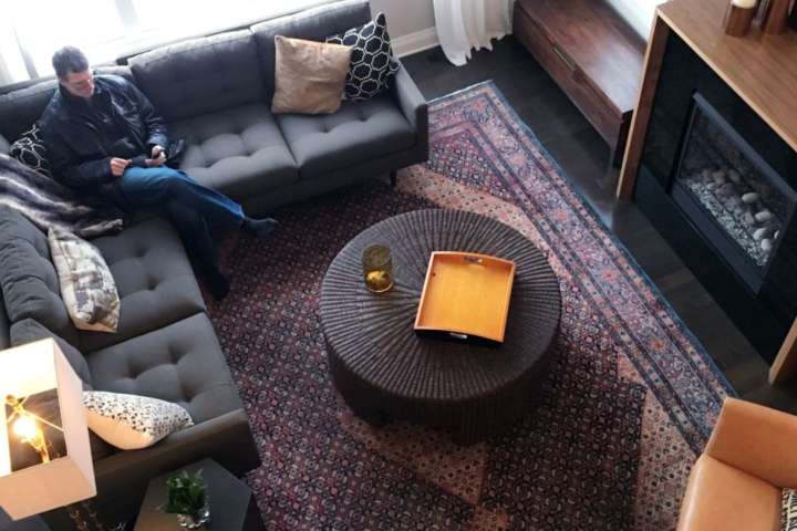 man sitting on his sofa with a large decorative rug