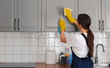 woman cleaning kitchen cupboard