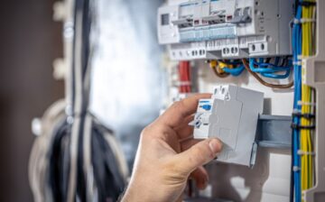 male electrician works switchboard with electrical connecting cable