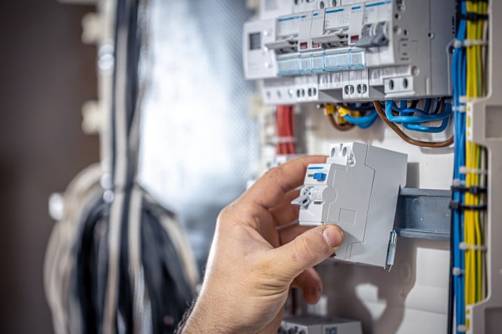 male electrician works switchboard with electrical connecting cable